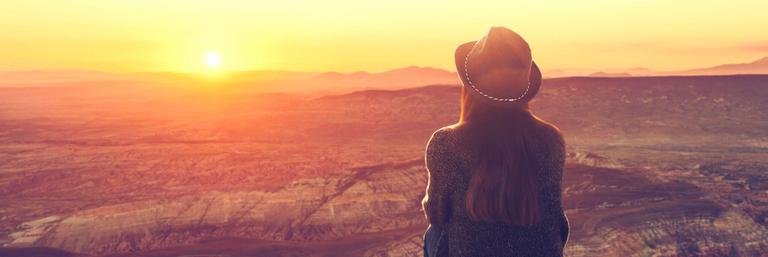 A photo of a girl looking off in the distance at a sunset in the desert.