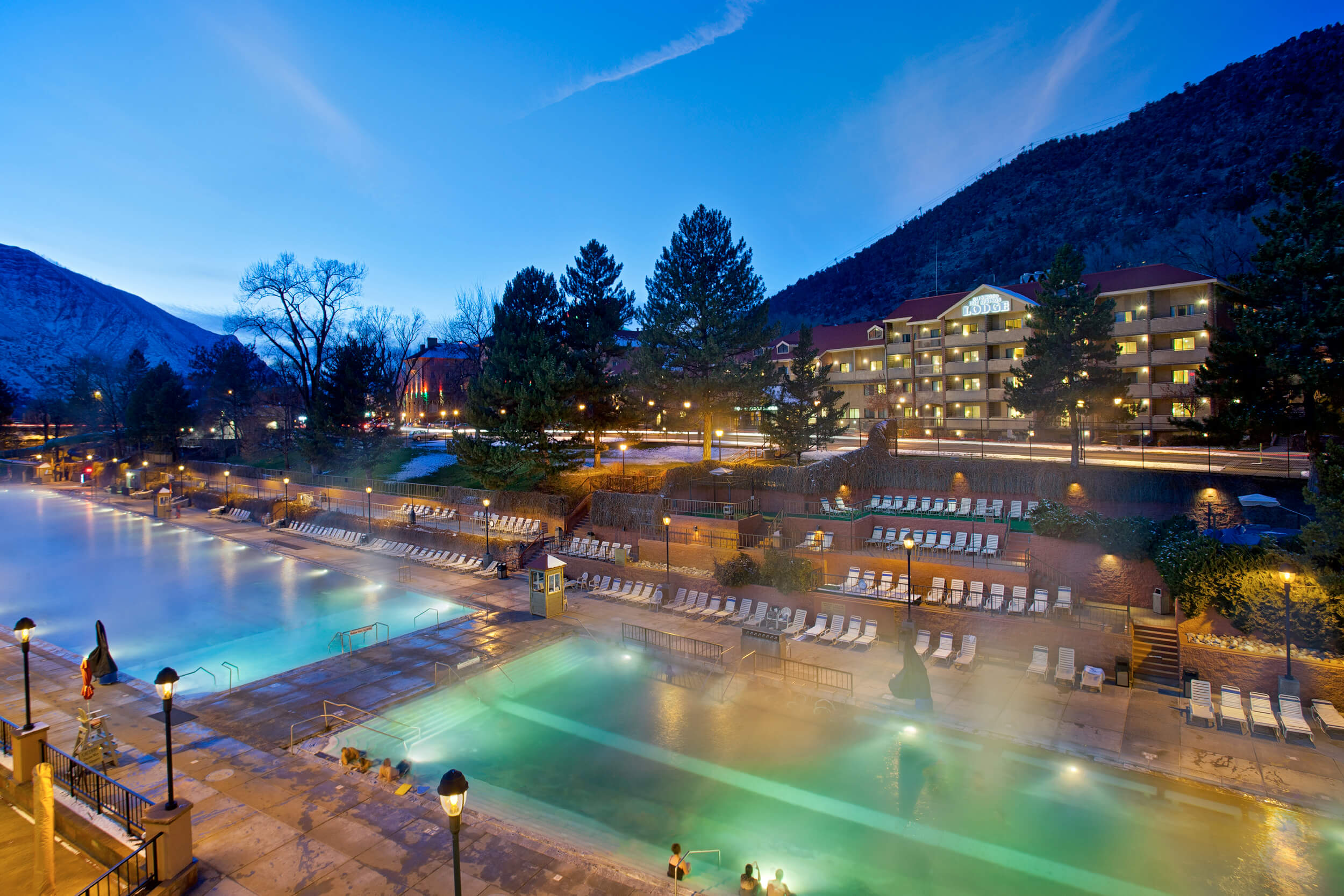 This enchanting image captures the Glenwood Hot Springs pool during the evening. The mineral water releases gentle steam, creating a mystical atmosphere. The resort's lights elegantly shimmer on the pool's surface and in the surroundings, enhancing the serene and inviting ambiance of this nighttime oasis.