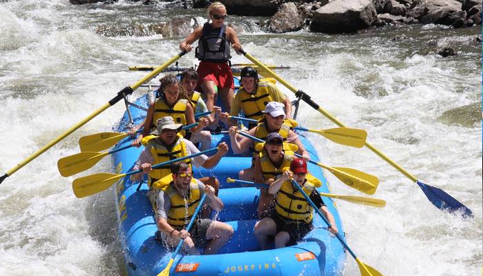 This image features a family joyfully navigating the Shoshone Rapids with their raft guide.