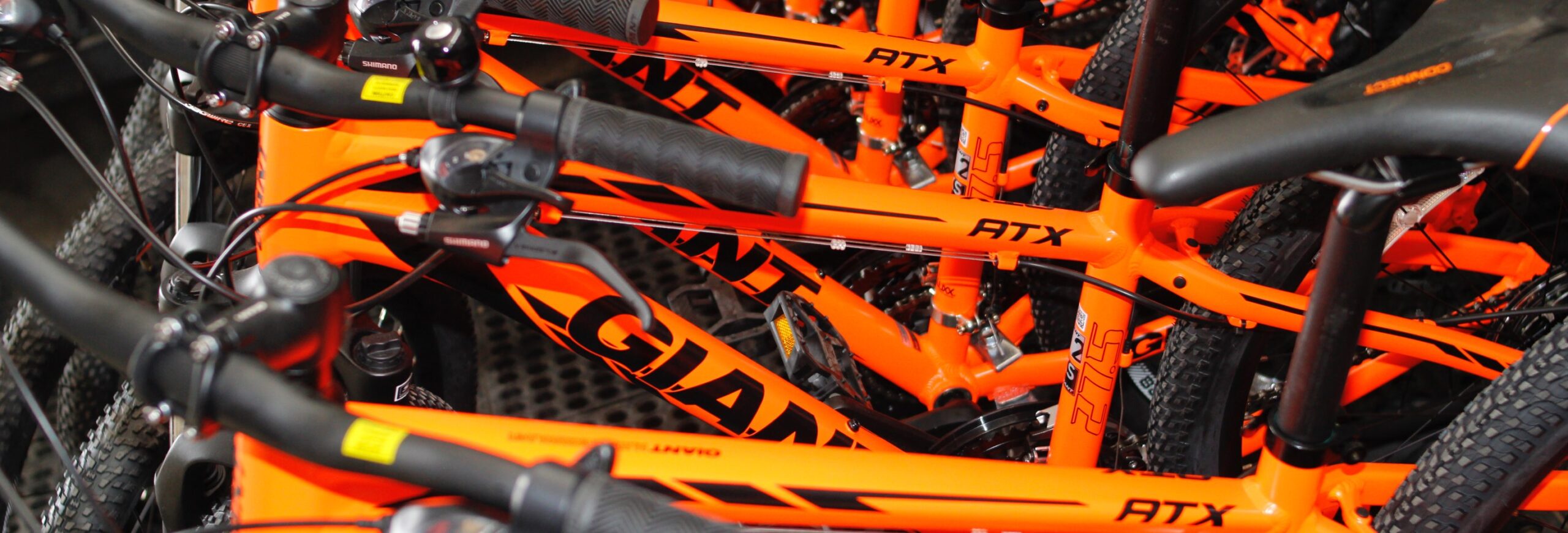 This close-up image captures a stack of vibrant orange Giant bikes, arranged closely together. The bold color of the bikes creates a visually striking and dynamic composition, emphasizing the unity of the neatly arranged two-wheelers.