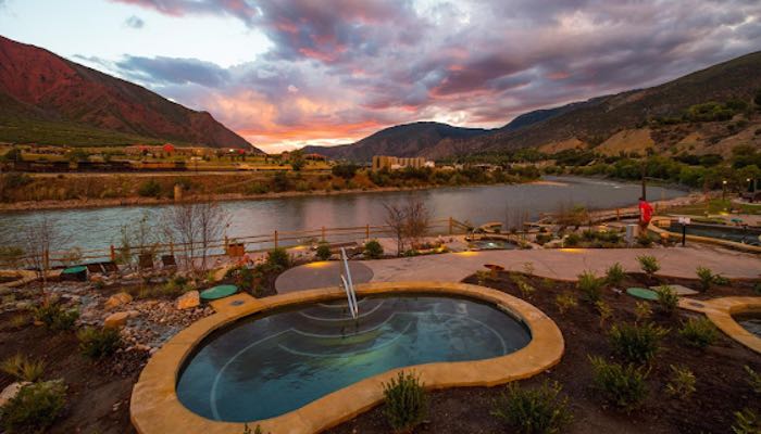 In this photograph, a hot pool at Iron Mountain Hot Springs Resort is showcased, offering a serene and tranquil atmosphere as it overlooks the river.