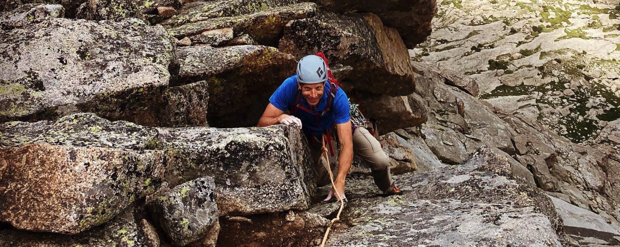 In this captivating photo, a rock climber fearlessly scales a rock with the aid of a rope, harness, and helmet. Despite the challenge, a confident smile graces his face, portraying the joy and ease he finds in conquering the ascent. This image encapsulates the thrill of rock climbing, blending adventure and a sense of accomplishment against the rugged backdrop of the climbing environment.
