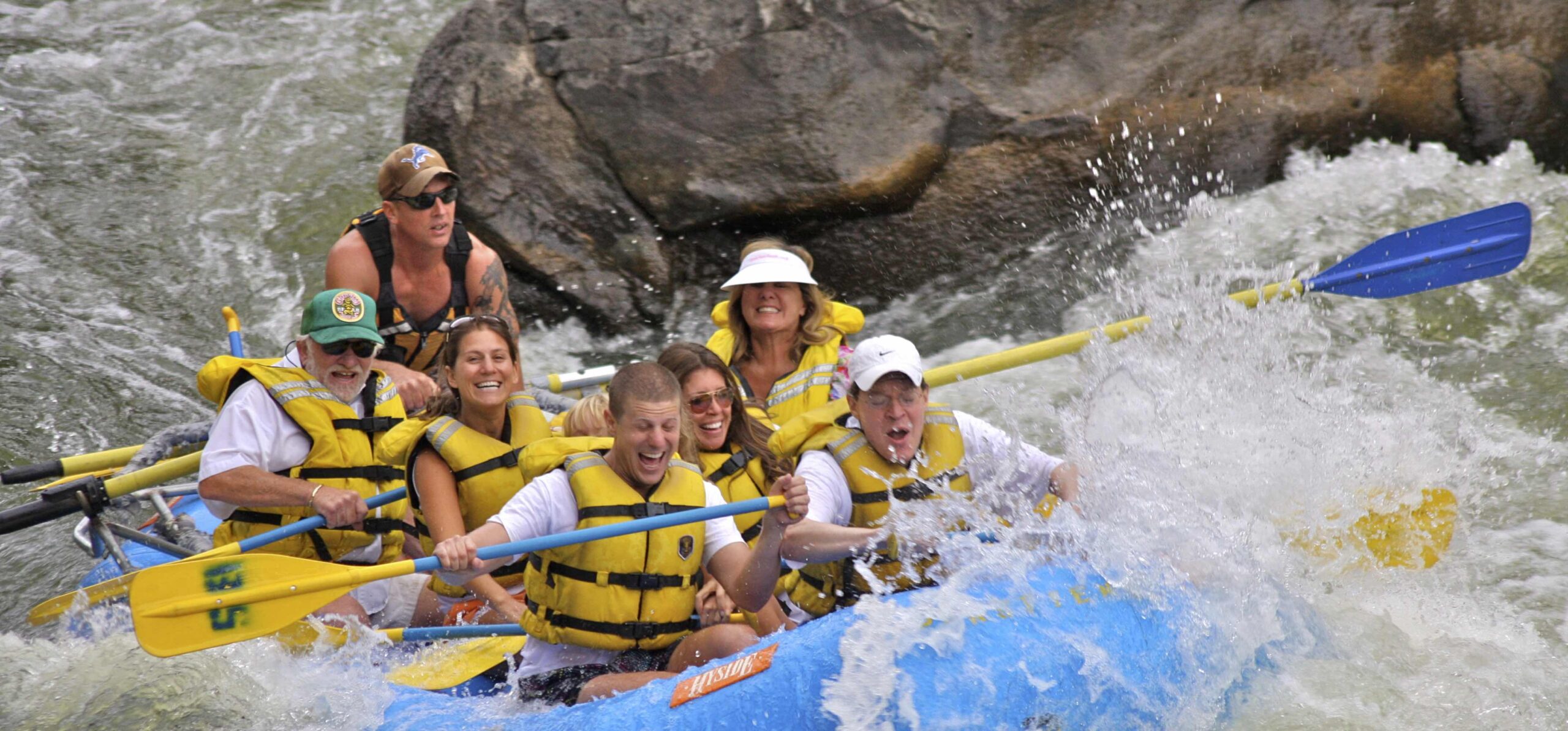 In this lively photo, a boat of rafters and their guide navigate the thrilling Shoshone Rapids on the Colorado River. Splashes of water surround them as they paddle, wearing bright smiles that reflect the sheer enjoyment of the moment.
