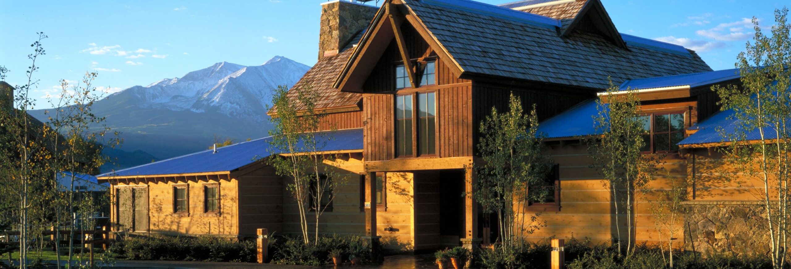 In this image, the River Valley Ranch golf course clubhouse is showcased against a backdrop of snowcapped mountains.