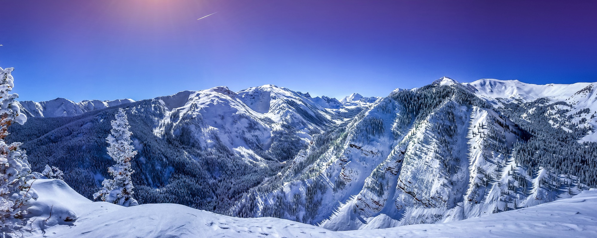 A serene landscape photo of snow-capped mountains and a clear blue sky.