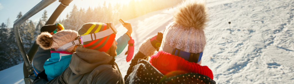 This is a photo of a group of people riding a chair lift on a sunny day or skiing and snowboarding.